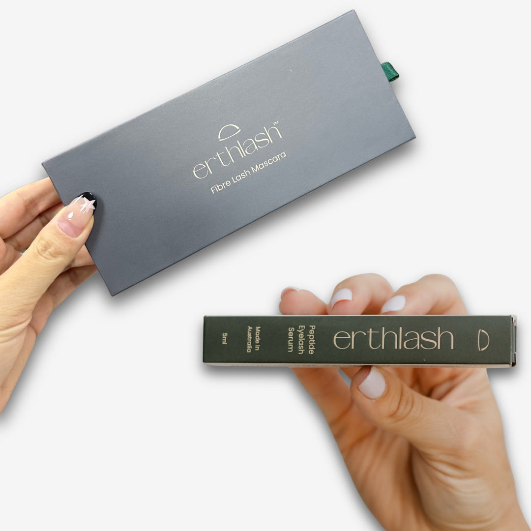 Hands holding a grey erthlash Fibre Lash Mascara box and a green erthlash Peptide Eyelash Serum 5ml box.